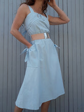 Charger l'image dans la galerie, Robe Couleurs Vintage est douce et romantique, ornée d'un élégant décolleté qui se noue au dos et laisse entrevoir quelques centimètres de peau. Ses bretelles cachent le soutien-gorge. Élaborée en coton, elle offre une bonne tenue. Sa taille élastiquée s'ajuste à la morphologie de chacune. Deux poches latérales se referment avec un nœud. Taille M, 38, 40